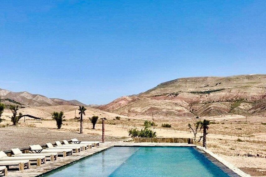 A swimming pool with lounge chairs, surrounded by desert hills. 2