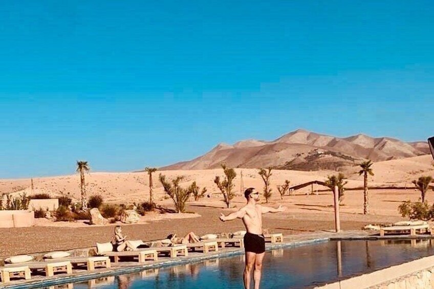 A desert landscape with a swimming pool, palm trees, and mountains in the background. 2
