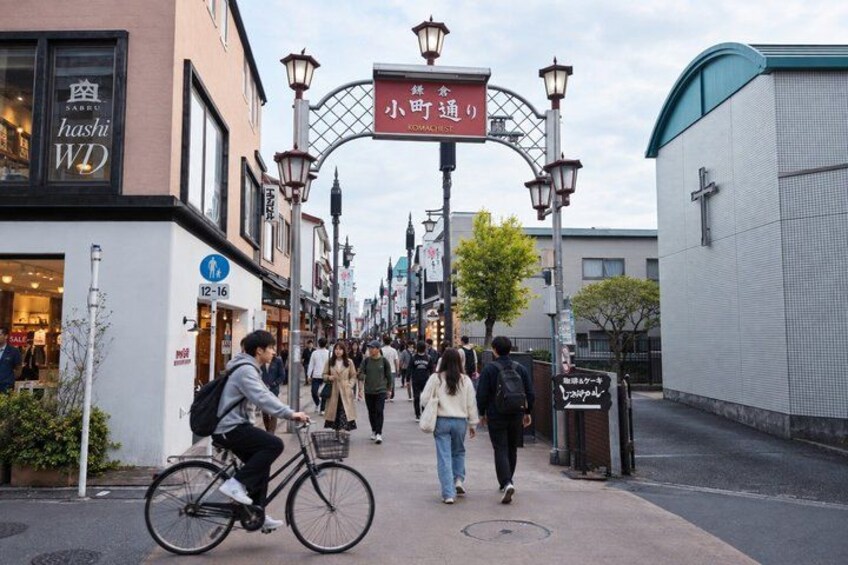 A street with pedestrians, a cyclist, and storefronts. 5