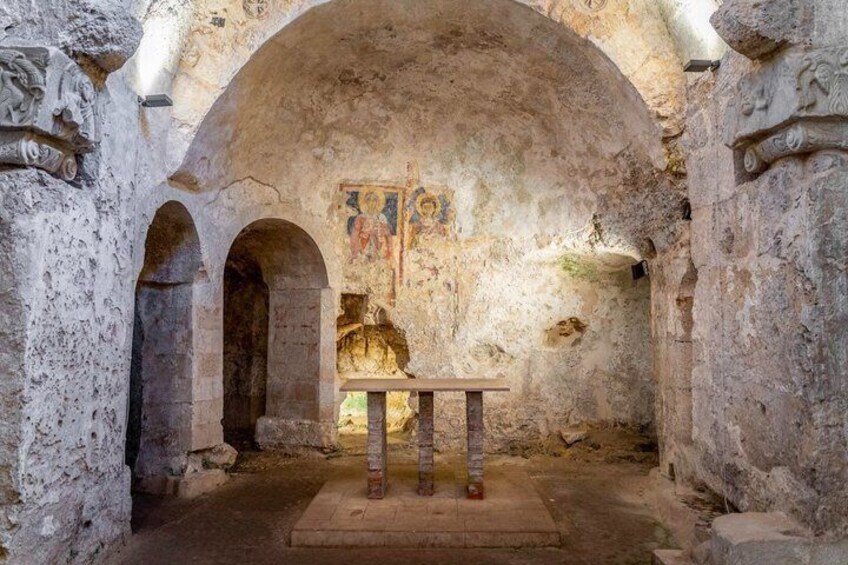An ancient stone structure with arched doorways and a central table. 5