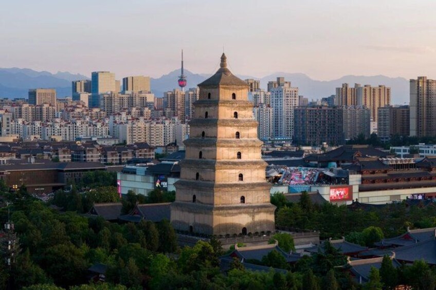 A historic tower in a cityscape with modern buildings and mountains in the background. 4