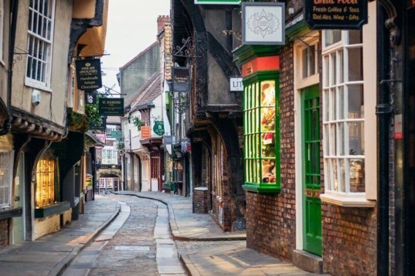 A narrow street with brick buildings, a green awning, and a sign for a cafe. 3