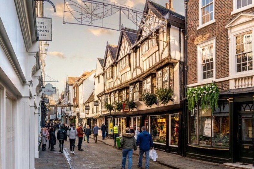 A bustling street with Tudor-style buildings, a sign for 'The White Company,' and pedestrians. 5