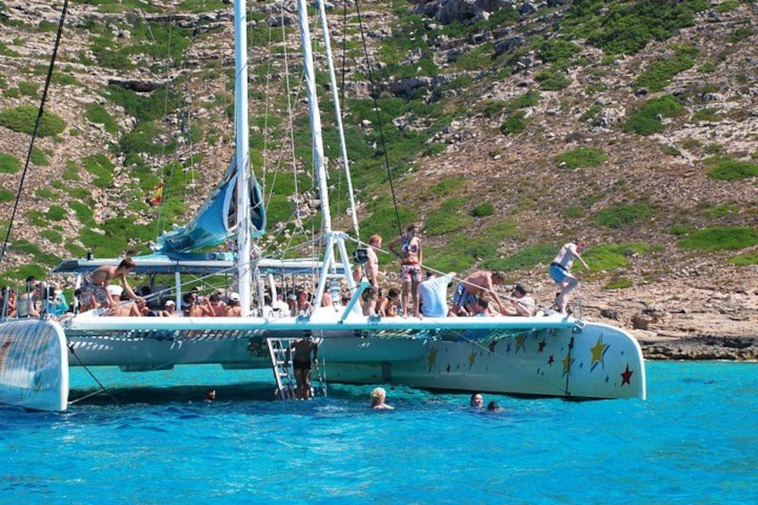 A sailboat with people on board, surrounded by clear blue water and a rocky coastline. 5