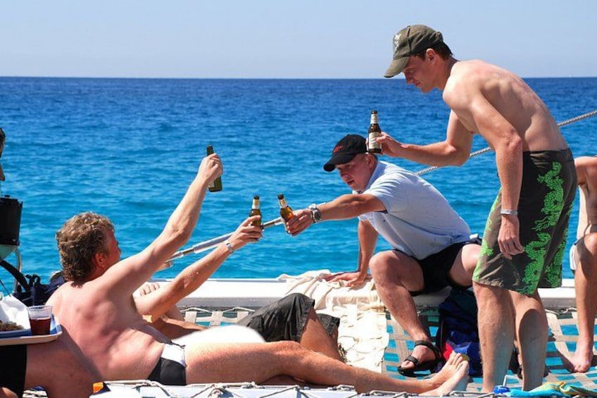 People on a boat, some holding drinks, with the ocean in the background. 3