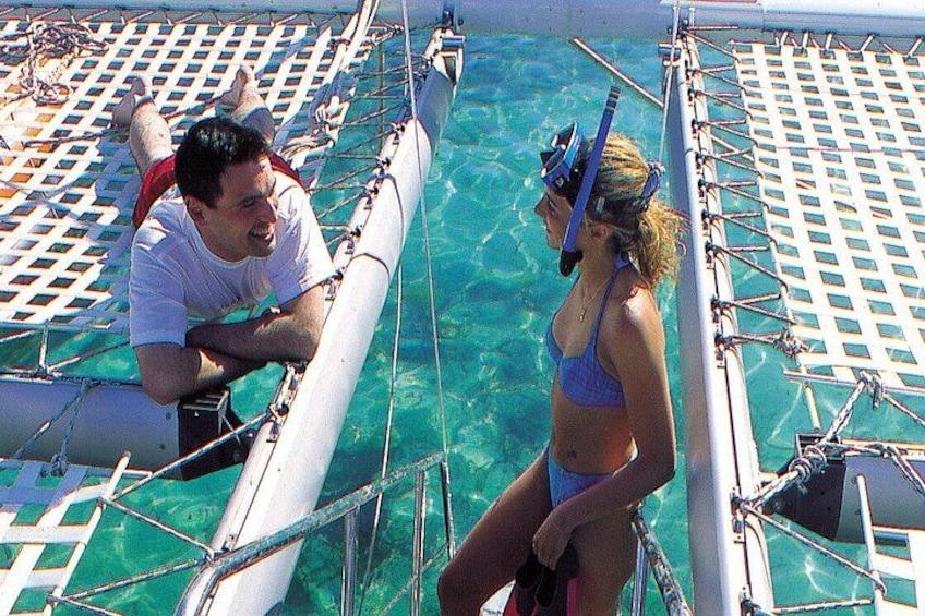 A person in a blue swimsuit and snorkel gear on a boat, another person in a white shirt, and a clear blue sea. 2