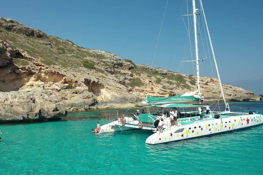 A sailboat with colorful decorations docked near rocky cliffs. 2