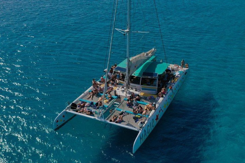 A sailboat with multiple passengers, a mast, and a green canopy on the deck. 4