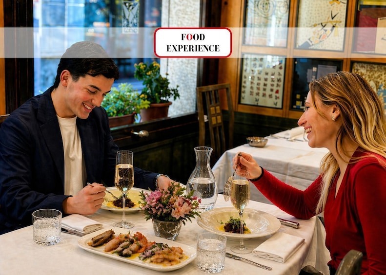 A couple dining at a restaurant with a table set for a meal, wine glasses, and a floral centerpiece. 1