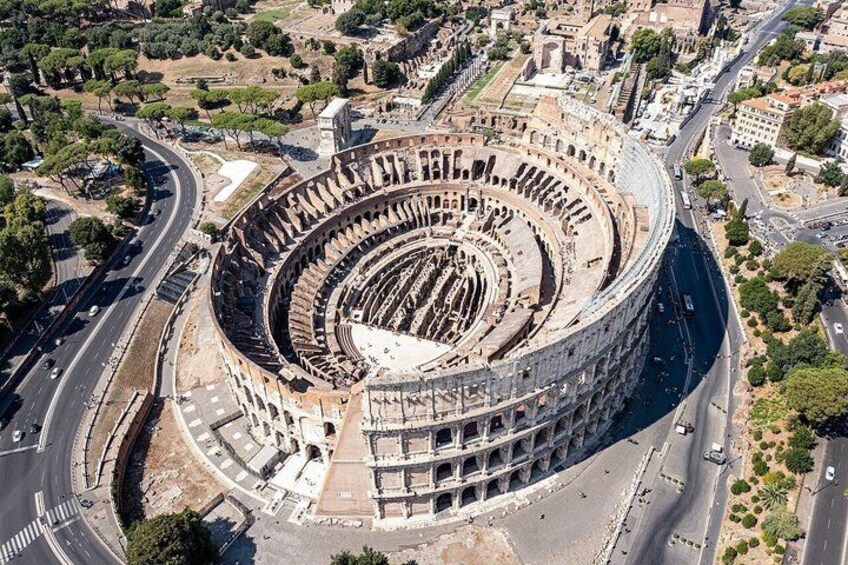 A large historical amphitheater with multiple levels of seating, surrounded by modern roads and buildings. 5