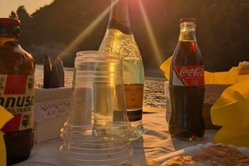 A table with bottles, glasses, and a Coca-Cola bottle on a beach with a sunset in the background. 5