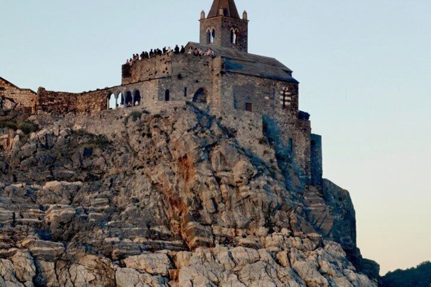 A historic stone fortress with a bell tower, perched atop a rocky hill. 2