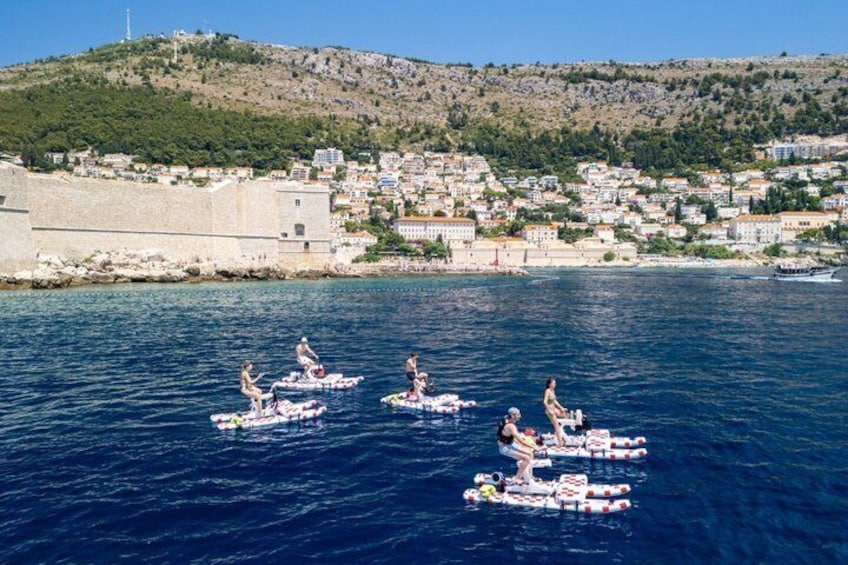 People on inflatable rafts in a body of water with a coastal town in the background. 3