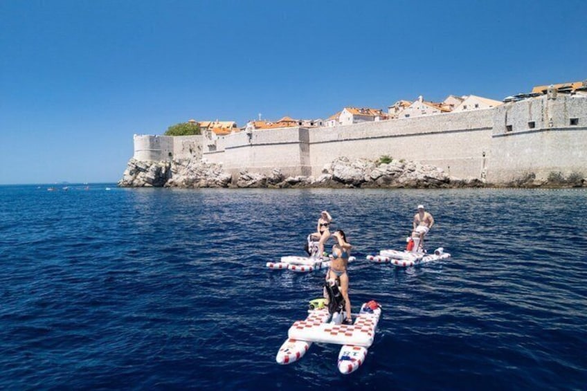 People on paddleboards in the water with a historic fort in the background. 2