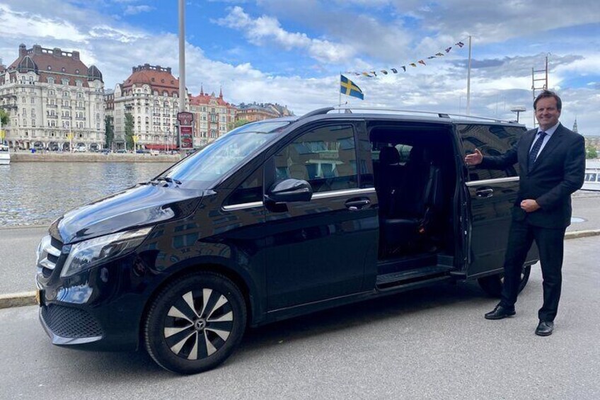 Un fourgon noir est garé au bord de l’eau, avec une vue sur la ville en arrière-plan. 2