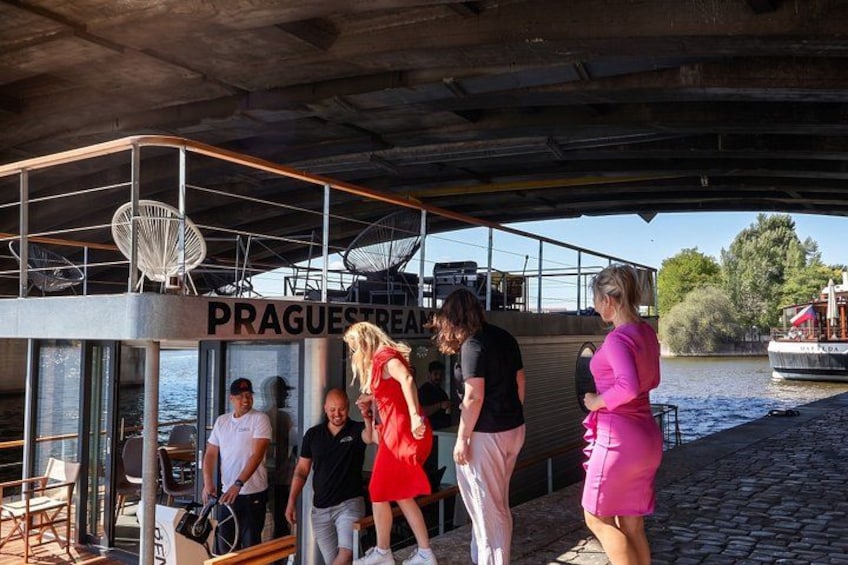 A group of people on a boat with a sign that reads 'PRAGUESTREAM.' 3