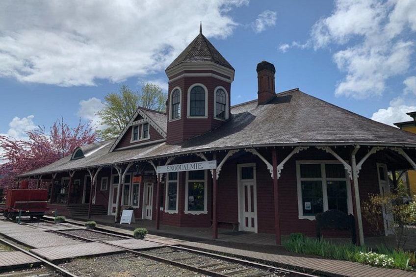 A vintage train station with a red facade and a distinctive tower. 2