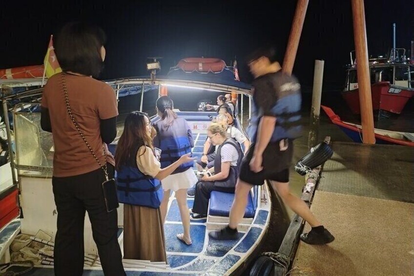 A group of people on a boat, some wearing life jackets, with a lifebuoy visible. 4