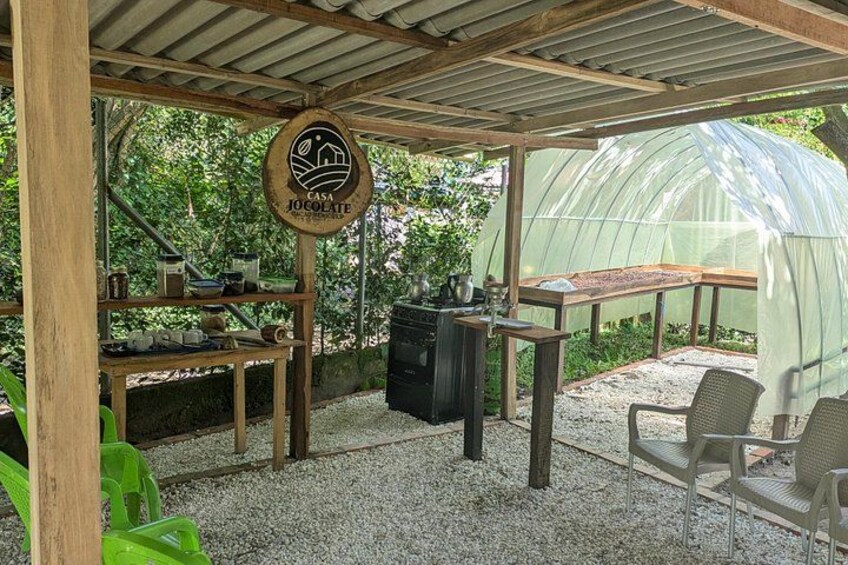 A greenhouse with a wooden table and chairs, a sign reading 'Casa Chocolat', and a green chair. 2