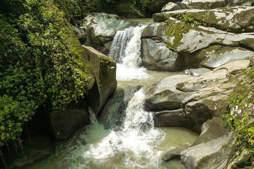 A waterfall cascading over rocks in a forested area. 3