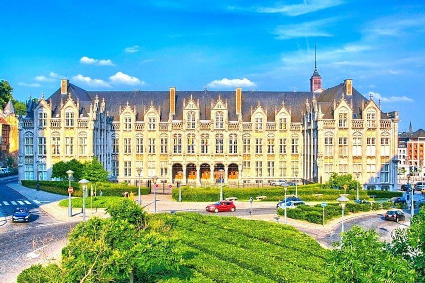 A large, ornate building with a symmetrical facade, surrounded by lush greenery and a clear blue sky. 1