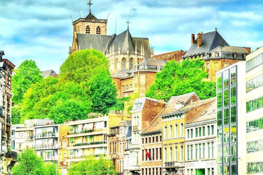 A historic town with a prominent church tower, lush green trees, and a mix of traditional and modern buildings. 3