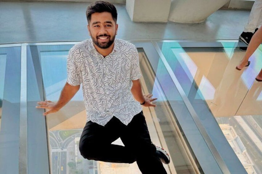 A person sitting on a glass floor with a cityscape view. 2