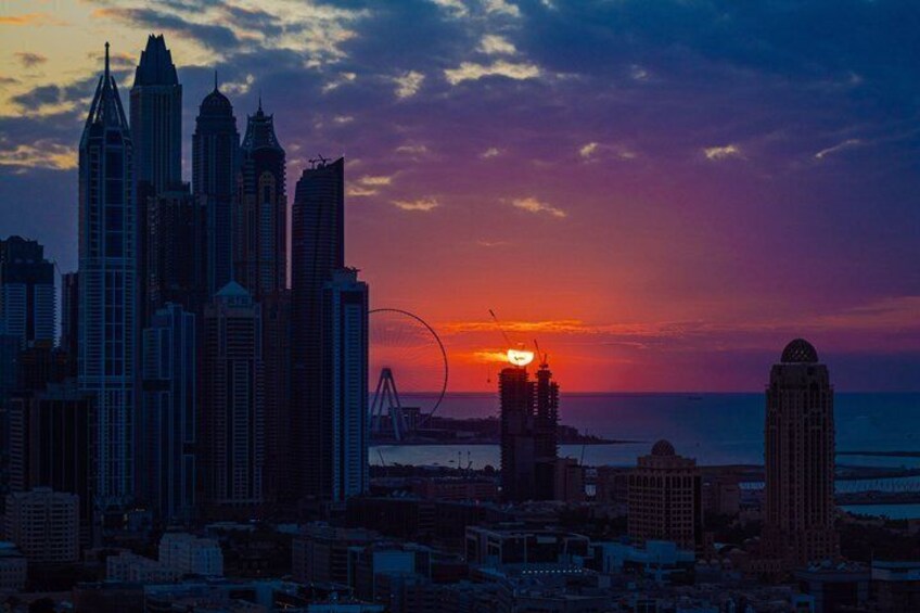 A city skyline at sunset with high-rise buildings and a bridge in the background. 4