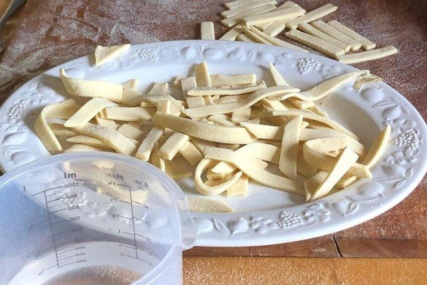 A plate of pasta, a measuring cup, and a wooden table. 4