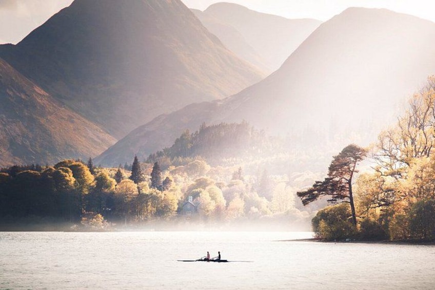 A calm lake with a boat, surrounded by mountains and trees. 3