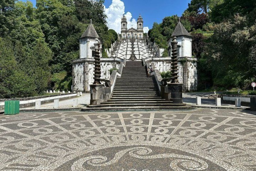 A grand staircase leading to a castle-like structure surrounded by lush greenery. 1