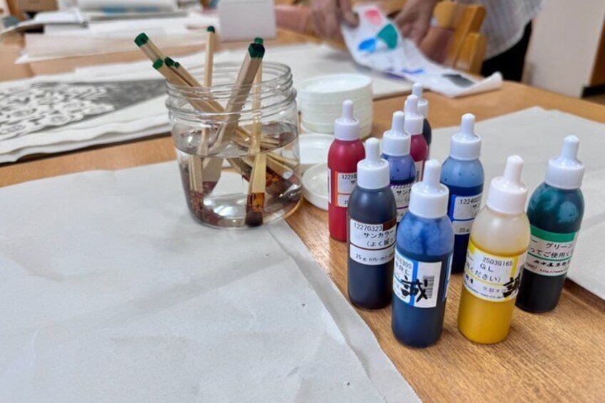 A table with ink bottles, brushes, and paper, likely in a workspace. 1