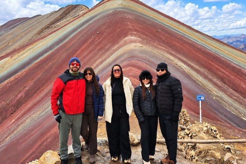 A group of people standing in front of a colorful geological formation. 2