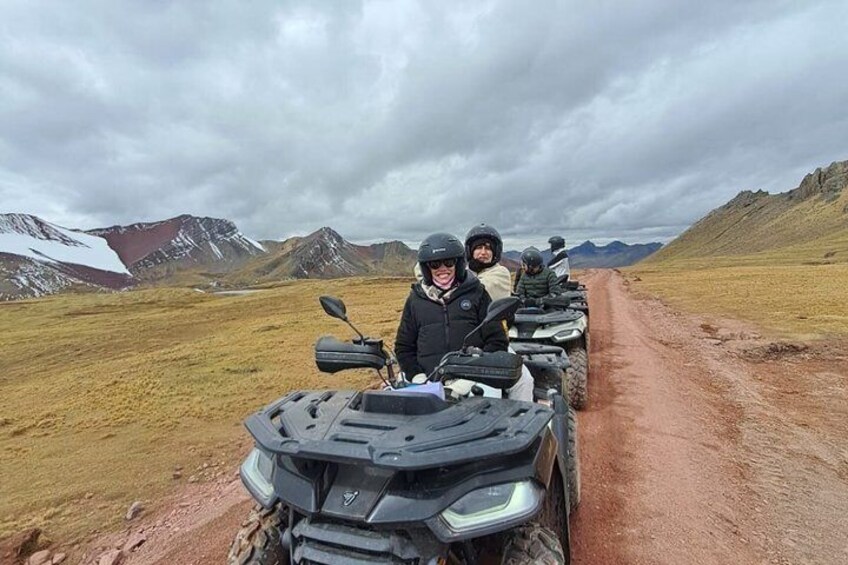 A group of people on ATVs on a dirt road with mountains in the background. 4