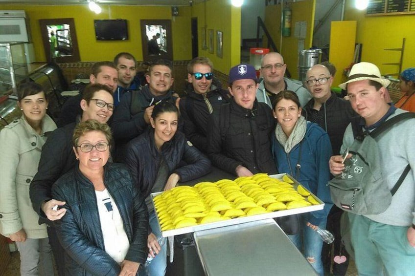A group of people gathered around a table with a large tray of yellow bananas. 4