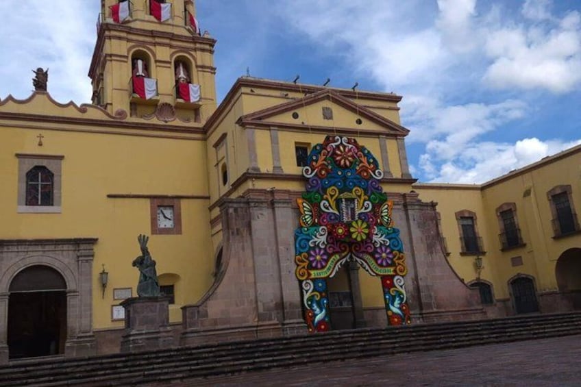 A yellow building with a bell tower and a colorful archway. 5
