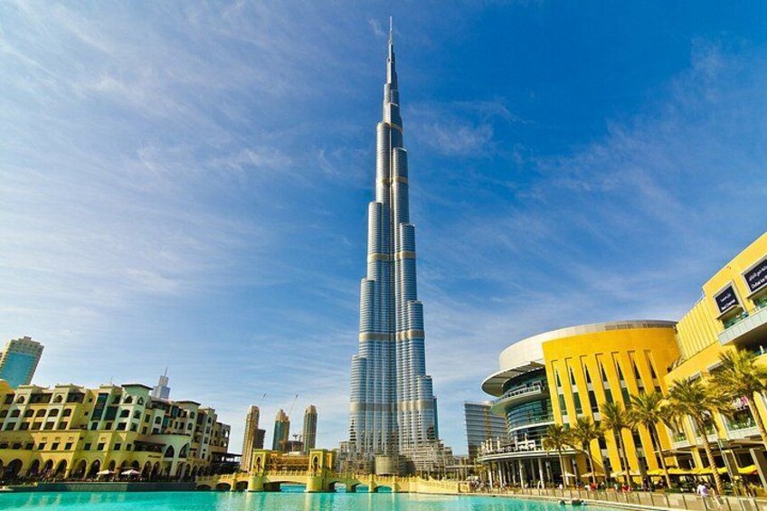 A tall skyscraper, a body of water, and surrounding buildings. 1