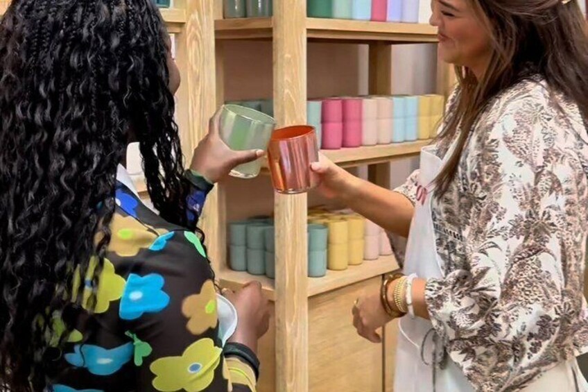 Two people holding mugs in front of a shelf with colorful spools. 5