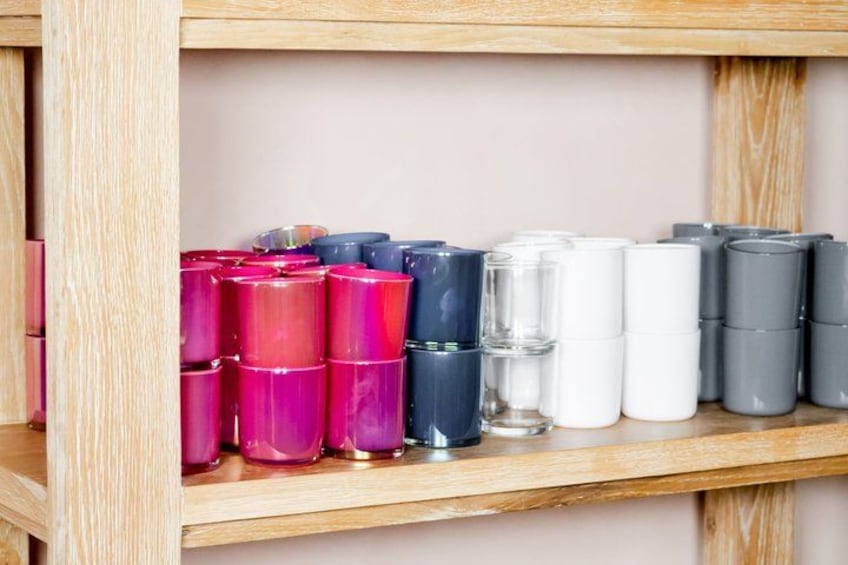 A wooden shelf with various cylindrical containers in different colors. 2