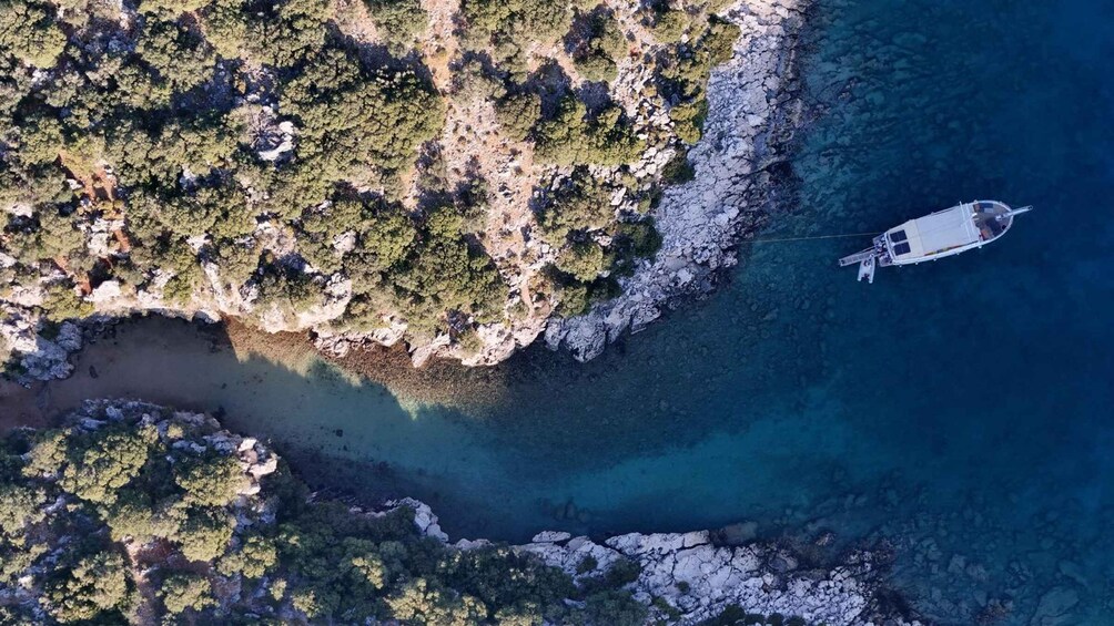 A boat anchored near a rocky coastline with clear waters. 4