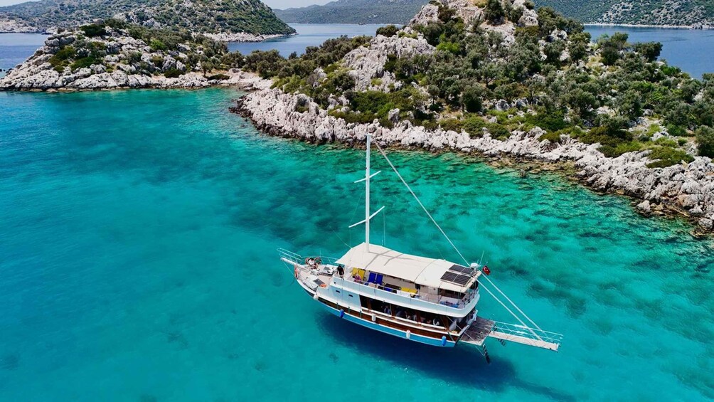 A boat anchored near a rocky island surrounded by clear turquoise waters. 2