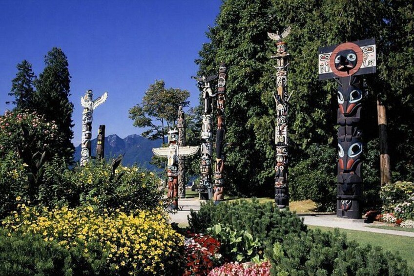 Totem poles in a garden with mountains in the background. 4