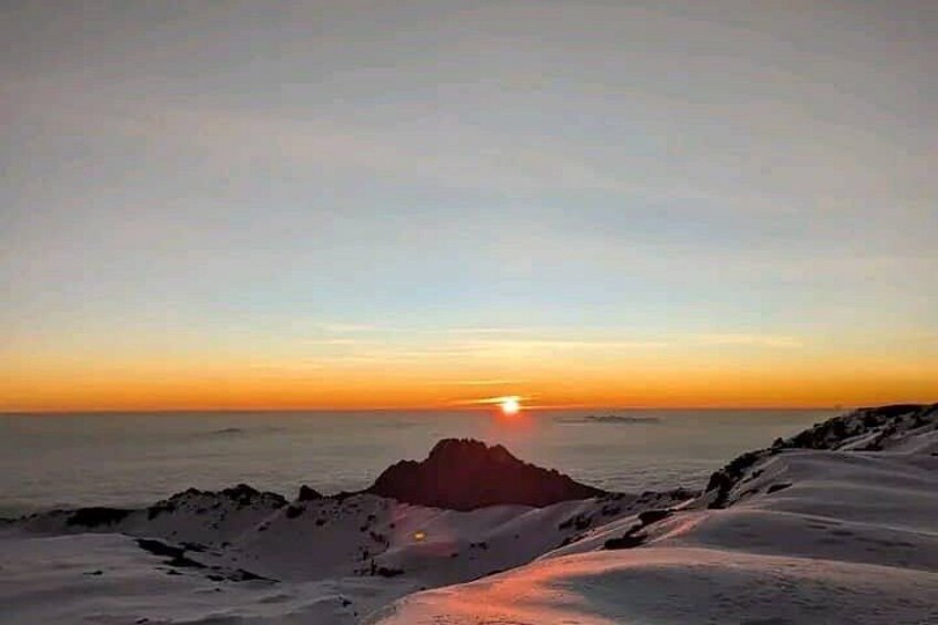A sunset over a snowy landscape with a rocky outcrop in the foreground. 2