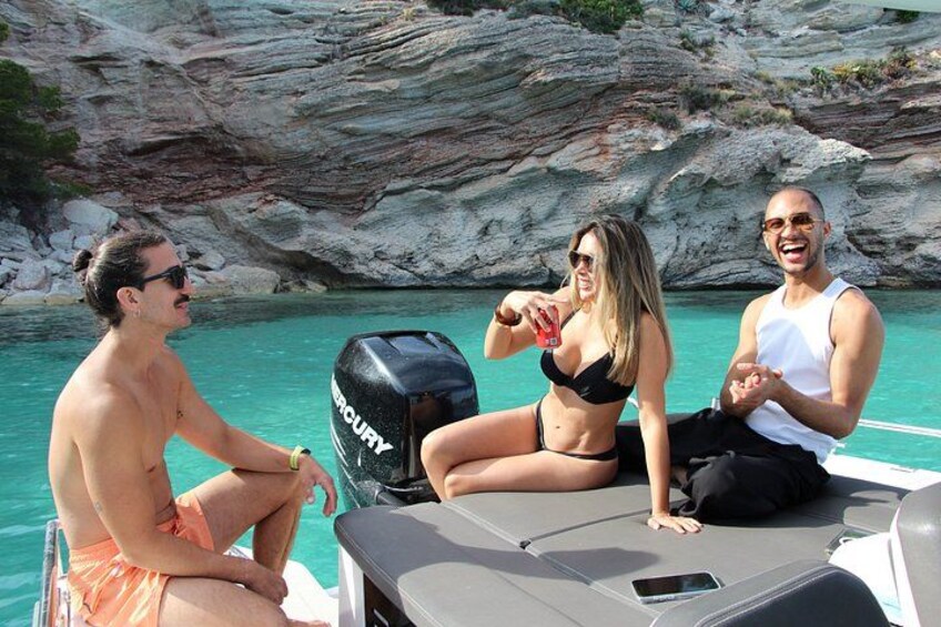 Tres personas en un bote cerca de acantilados rocosos y aguas turquesas. 4