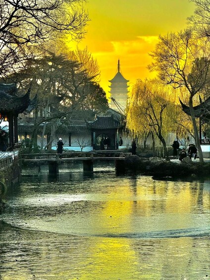 A traditional Chinese pagoda, a bridge, and a reflection in water. 4