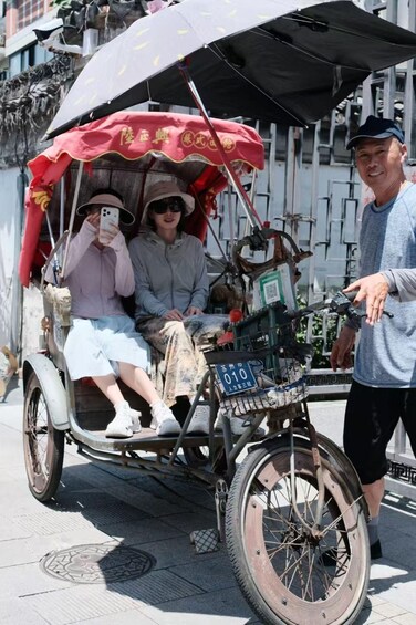 A rickshaw with a red canopy, a person taking a photo, and another person standing beside it. 2