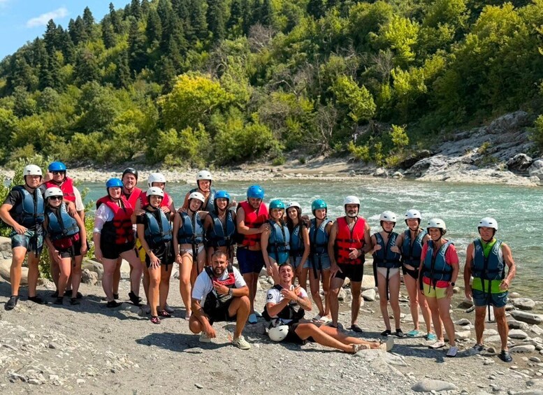 A group of people wearing life jackets and helmets by a river. 2