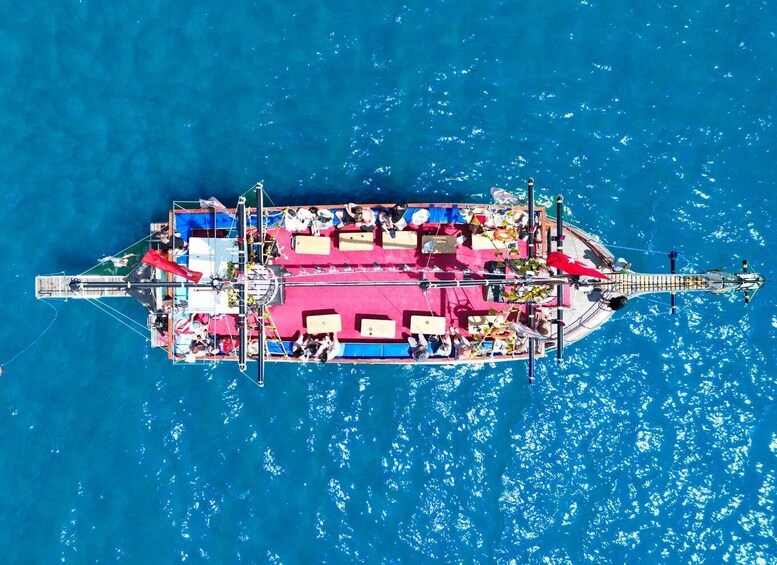 A boat with a pink deck, people on board, and a clear blue sea. 4