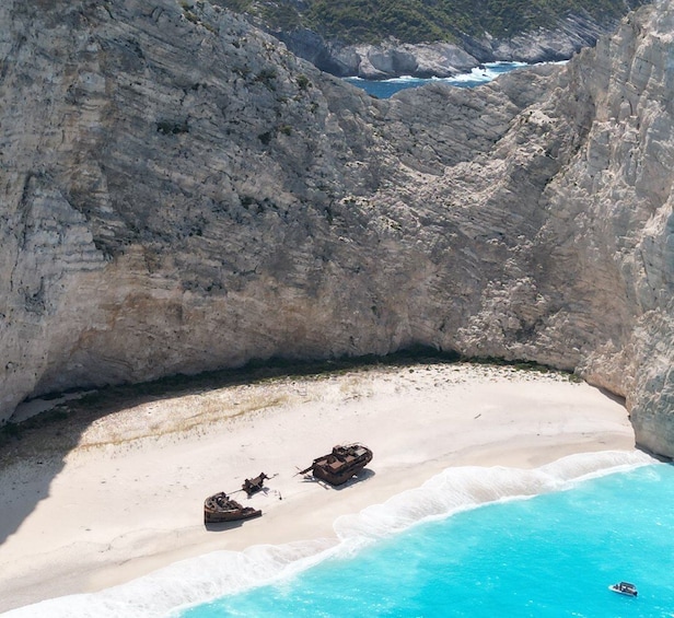 A coastal landscape with a rocky cliff, a sandy beach, and a clear blue sea. 3
