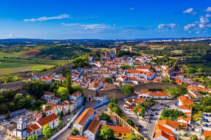 A historic town with white buildings, a central square, and surrounding greenery. 3